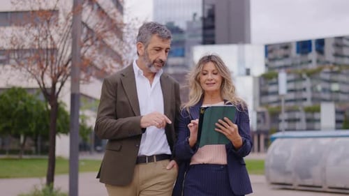 Business Professionals Reviewing Tablet While Walking Outdoors