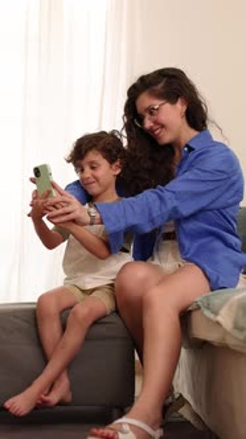 Woman and boy posing for smartphone photo at home