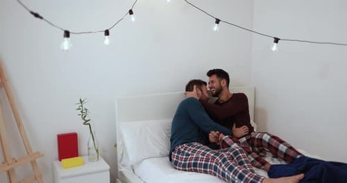 Affectionate Male Couple Embracing on Bed at Home