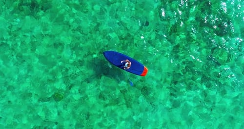 Aerial View of Woman in White Swimsuite Standing on Sup Board with Paddle on Crystal Turquoise Water