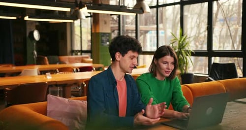 Colleagues Brainstorming New Ideas Using Laptop in Modern Cafe