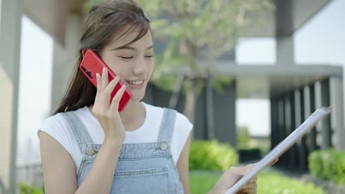 Woman Talks on Phone with Clipboard Outdoors