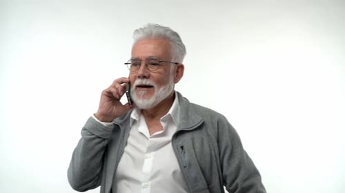 Portrait of an Elderly Retired Man in Glasses Talking on a Mobile Phone on a White Background