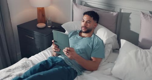 Man Relaxing in Bed Using Tablet at Home