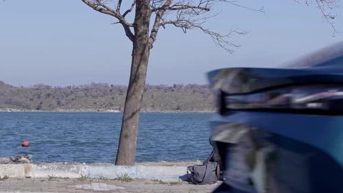 Woman Sits Smoking Cigarette on Lakefront Wall