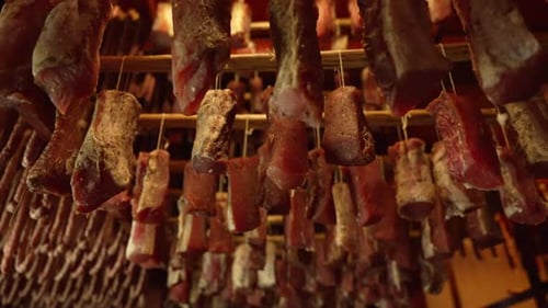 Cured Meats Hanging in a Dark Room
