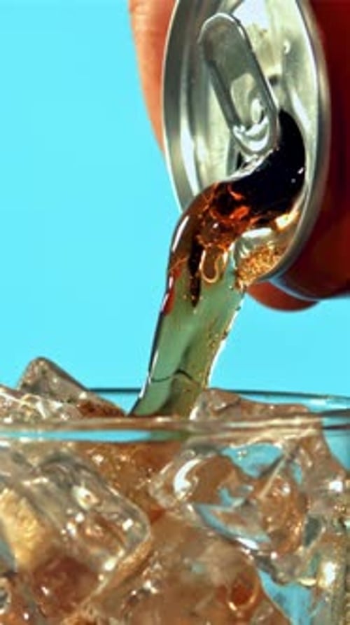 Cola is Poured From a Can Into a Glass
