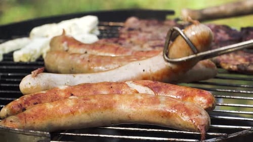 Turning Meat and Sausages on the Grill for a Tasty Outdoor Barbecue