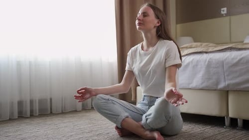 Woman Meditating in Lotus Position in Bedroom