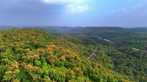 The roads are visible from the dense forest on the valley, curving through the green landscape.
