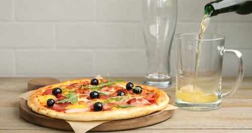 Pouring Beer into Mug Beside Pizza with Olives