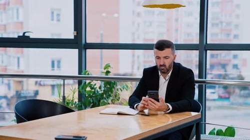 Man Using Mobile Phone at Office Table