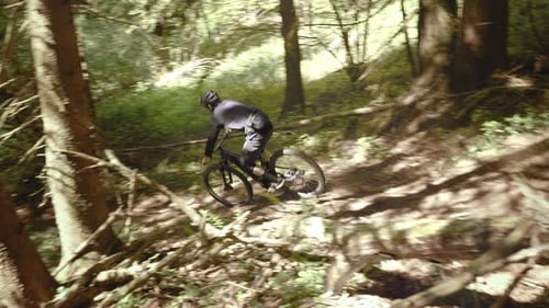 Amazing shot of a young athletic man on MTB e-bike jumping down the rock. Extreme sport.