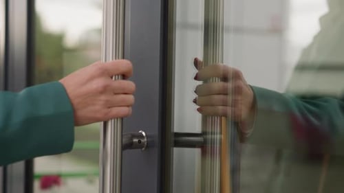 Hand of Elegant Woman Opening Glass Door of Office Building