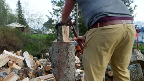 Person chopping wood in Norway yard surrounded by forest and tools