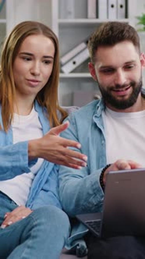 Young Couple Laughing While Using a Laptop