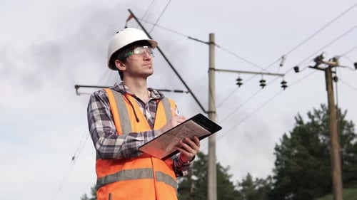 The power engineer inspects the high-voltage power line and records the data.