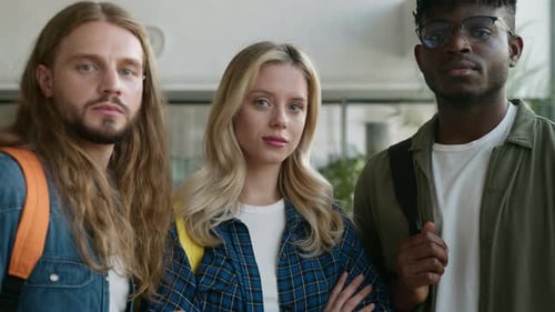Three young adults smiling indoors at the camera