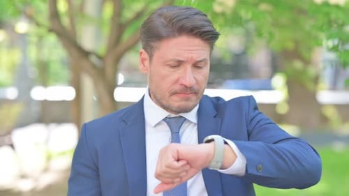 Anxious Businessman Checks Watch Outdoors