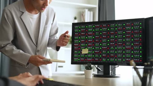 Man Writes Financial Data While Colleague Types Nearby