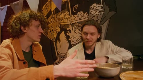 Man Casually Talking to his Friend While Having Drinks and Snacks at Bar Counter