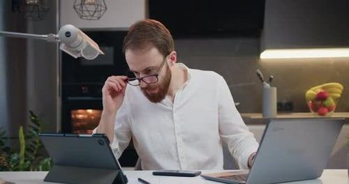 Young man entrepreneur using laptop writing notes in modern at home office desk. Online from home