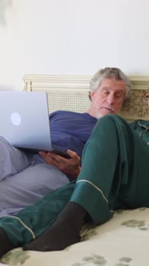 Senior Couple Relaxing in Bed with Laptop