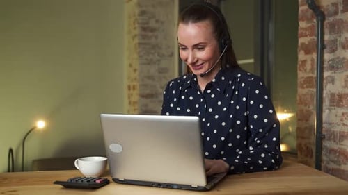 Woman With Headset Working at Laptop