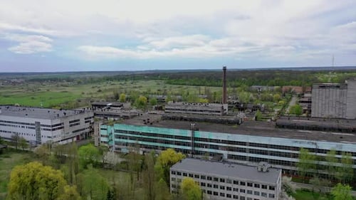 Large factory among beautiful green nature. Exterior of industrial plant in the countryside.