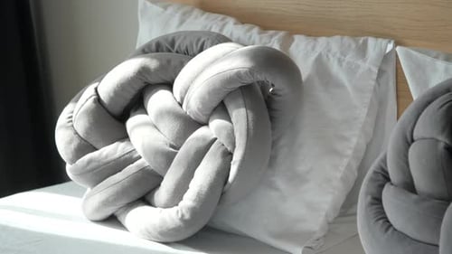 Stylish Knot Pillows on Bed with White Sheets