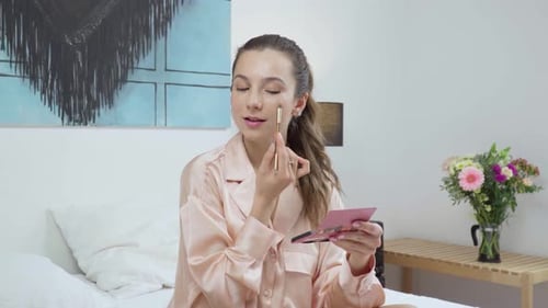 Woman Applying Makeup on Bed in Bedroom