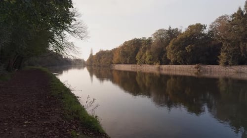 Calm autumn day along the Cher River with reflections of trees on the still water at golden hour
