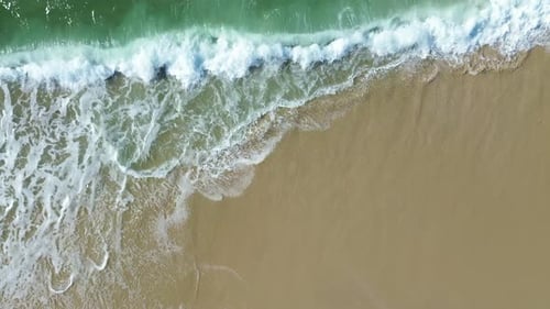 Vidéo aérienne par drone des vagues de l'océan Atlantique se jetant sur une plage de sable, belle vue de dessus de