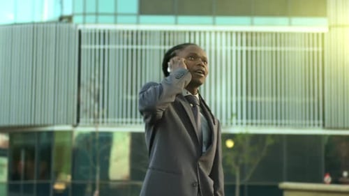 African american businessman walking and talking on mobile phone at sunrise city