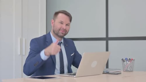 Man in Suit Giving Thumbs Up in Office
