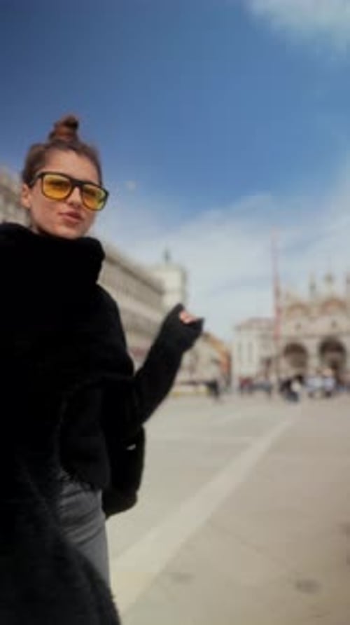 Una mujer en el centro histórico de Venecia con abrigo y gafas explora la arquitectura y los lugares emblemáticos