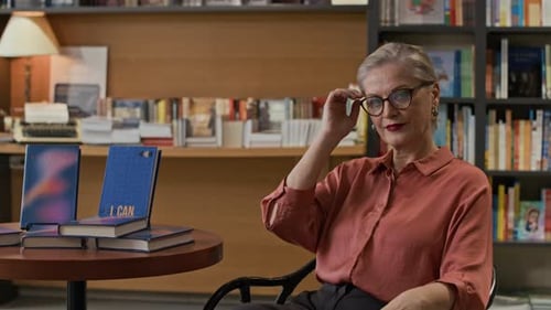 Confident Female Author Posing Beside Her Book Display at Bookstore