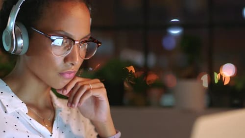 Femme d'affaires créative avec écouteurs, lunettes et ordinateur portable travaillant la nuit pour le numérique