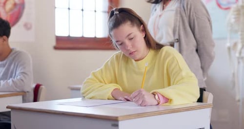 Student Writing at Desk in Classroom