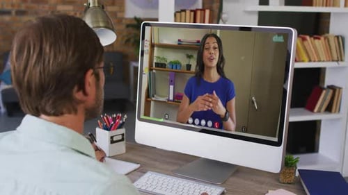 Caucasian male teacher having a video call with female colleague on computer at school