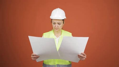 Engineer Reviewing Blueprints Wearing Hard Hat and Safety Vest