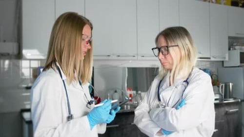Employees of laboratory veterinary clinic, young nurse and woman veterinarian discuss the diagnosis