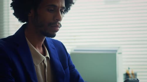 Pensive Manager Texting on Smartphone at Office Desk