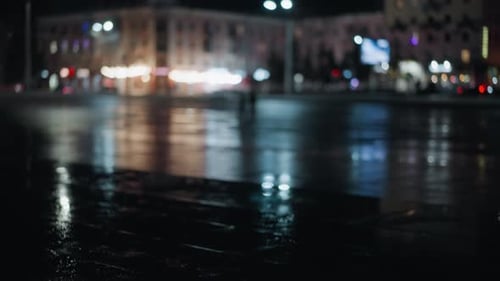 Rainy Night Street Reflections with Blurred Figures