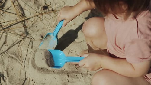 Child Plays with Sand on Sunny Beach Day