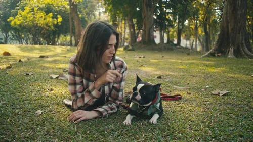 Woman Lying on Grass with Boston Terrier Dog