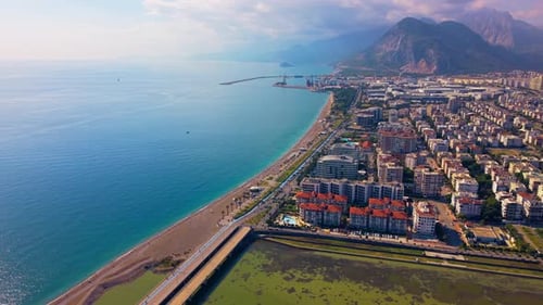 Aerial Reveal of Coastal Beachfront City and Mountains Along the Sea