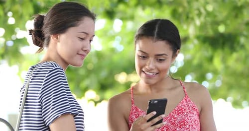 Two Cheerful Women Looking at a Mobile Phone