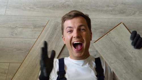 Cheerful Man Lying on New Wood Floor