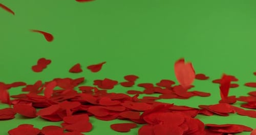 Falling heart-shaped confetti on a green background.